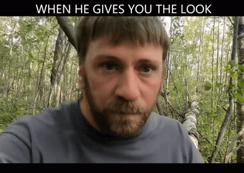 A Man With A Beard Is Standing In The Woods With A Caption That Says When He Gives You The Look GIF