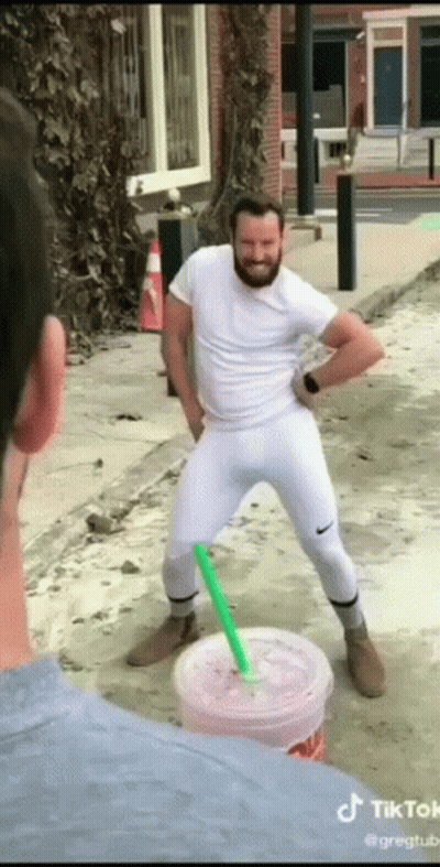 A Man With A Beard Is Standing Next To A Cup Of Drink With A Straw . GIF