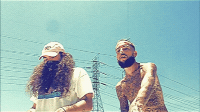 A Man With A Beard Is Standing Next To A Man With Long Hair GIF