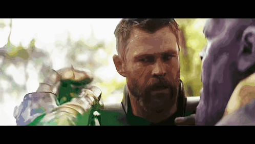 A Man With A Beard Is Standing Next To A Purple And Green Character . GIF