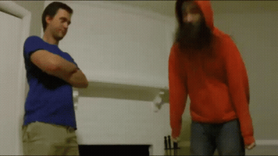 A Man With A Beard Is Standing Next To A Woman In An Orange Hoodie GIF