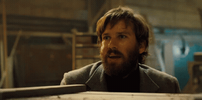 A Man With A Beard Is Standing Next To A Wooden Box And Making A Surprised Face . GIF