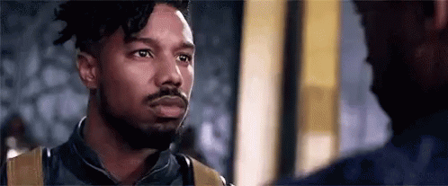 A Man With A Beard Is Standing Next To Another Man In A Room . GIF