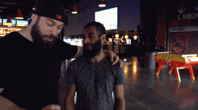 A Man With A Beard Is Standing Next To Another Man In Front Of A Lane Sign GIF