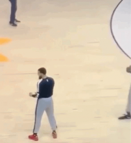 A Man With A Beard Is Standing On A Basketball Court With Another Man . GIF