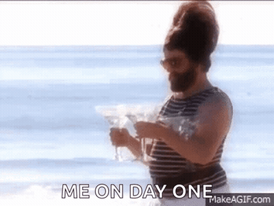 A Man With A Beard Is Standing On A Beach Holding A Martini Glass And Saying Me On Day One . GIF