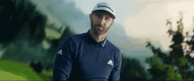 A Man With A Beard Is Standing On A Golf Course Holding A Golf Club . GIF