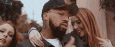 A Man With A Beard Is Surrounded By Two Women . GIF