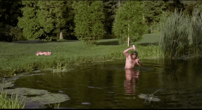 A Man With A Beard Is Swimming In A Pond . GIF