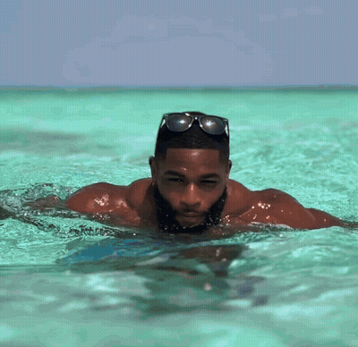 A Man With A Beard Is Swimming In The Ocean Wearing Sunglasses GIF