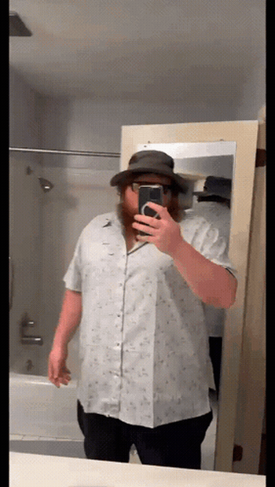 A Man With A Beard Is Taking A Selfie In Front Of A Mirror GIF