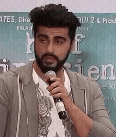 A Man With A Beard Is Talking Into A Microphone . GIF