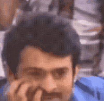 A Man With A Beard Is Talking On A Cell Phone And Smiling . GIF