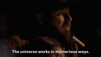 A Man With A Beard Is Talking On A Cell Phone In A Dark Room With The Words `` The Universe Works In Mysterious Ways '' GIF
