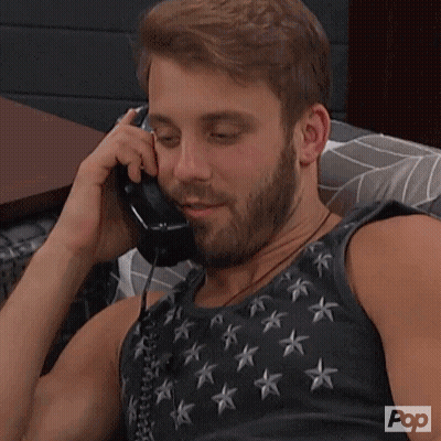 A Man With A Beard Is Talking On A Phone With Pop Written On The Bottom Of His Shirt GIF