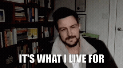 A Man With A Beard Is Talking On A Video Call In Front Of A Bookshelf . GIF