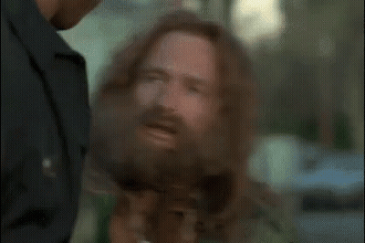 A Man With A Beard Is Talking To A Police Officer . GIF