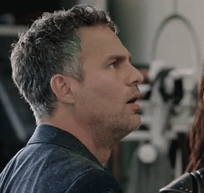 A Man With A Beard Is Talking To A Woman In A Room . GIF
