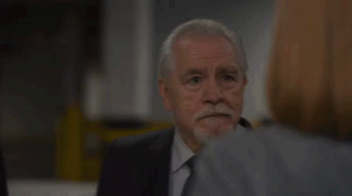 A Man With A Beard Is Talking To A Woman In A Suit And Tie . GIF