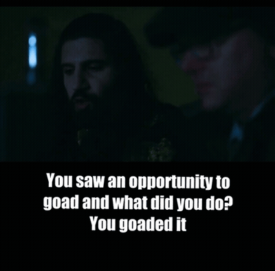 A Man With A Beard Is Talking To Another Man In A Dark Room GIF