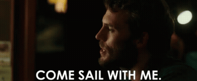 A Man With A Beard Is Talking To Another Man In A Dark Room . GIF
