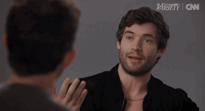 A Man With A Beard Is Talking To Another Man In Front Of A Variety Logo GIF