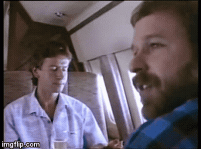 A Man With A Beard Is Talking To Another Man On A Plane . GIF