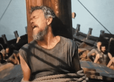 A Man With A Beard Is Tied To A Wooden Pole GIF