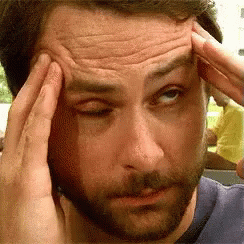 A Man With A Beard Is Touching His Forehead With His Hands GIF