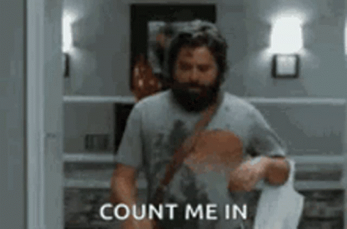 A Man With A Beard Is Walking Down A Hallway And Saying `` Count Me In '' While Holding A Bag . GIF