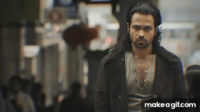 A Man With A Beard Is Walking Down A Street . GIF