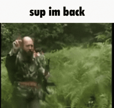 A Man With A Beard Is Walking Through A Field With The Words " Sup Im Back " At The Top GIF