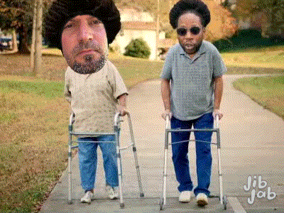 A Man With A Beard Is Walking With A Walker Next To Another Man With Sunglasses GIF