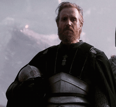 A Man With A Beard Is Wearing A Black Cape And Armor GIF