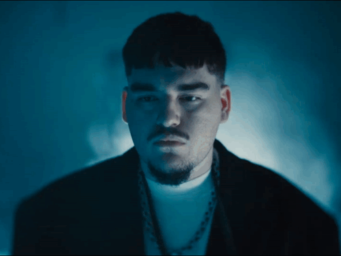 A Man With A Beard Is Wearing A Black Jacket And A White Shirt GIF