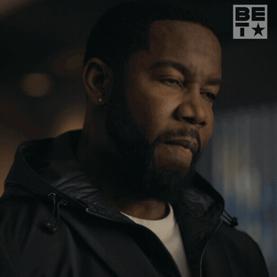 A Man With A Beard Is Wearing A Black Jacket That Says Fine GIF