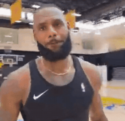 A Man With A Beard Is Wearing A Black Nike Tank Top . GIF