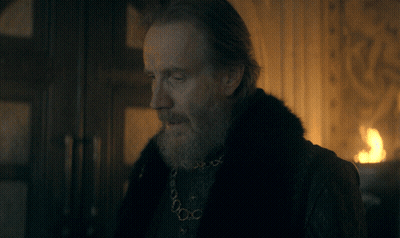A Man With A Beard Is Wearing A Black Shirt And A Gold Chain Around His Neck GIF