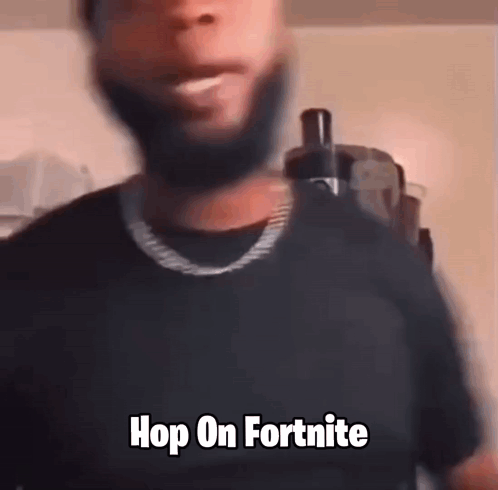 A Man With A Beard Is Wearing A Black Shirt And A Gold Chain . GIF