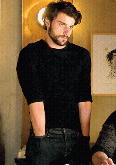 A Man With A Beard Is Wearing A Black Shirt And Jeans GIF