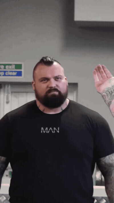 A Man With A Beard Is Wearing A Black Shirt That Says Man On It GIF