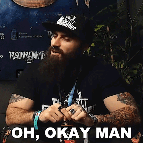A Man With A Beard Is Wearing A Black Shirt That Says " Oh Okay Man " GIF