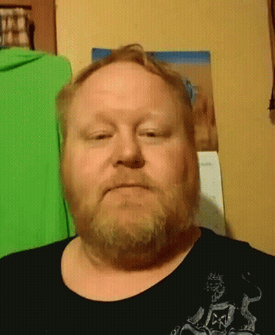 A Man With A Beard Is Wearing A Black Shirt With A Skull And Crossbones On It GIF