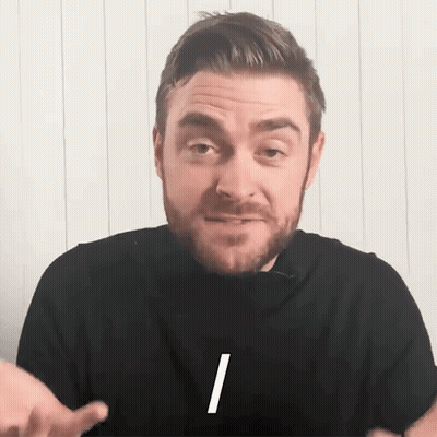 A Man With A Beard Is Wearing A Black Shirt With The Letter I On The Front GIF