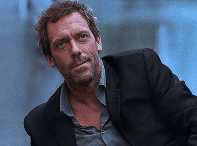 A Man With A Beard Is Wearing A Black Suit And A Grey Shirt GIF