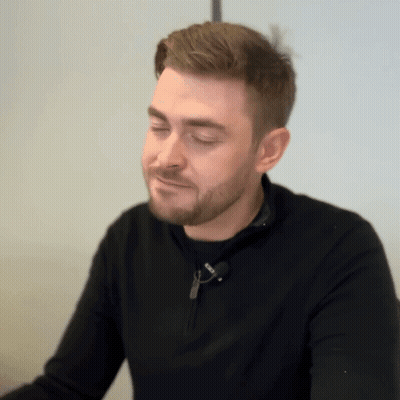 A Man With A Beard Is Wearing A Black Sweater With A Zipper On The Front GIF