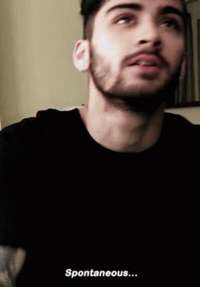 A Man With A Beard Is Wearing A Black T-Shirt And Says Spontaneous . GIF
