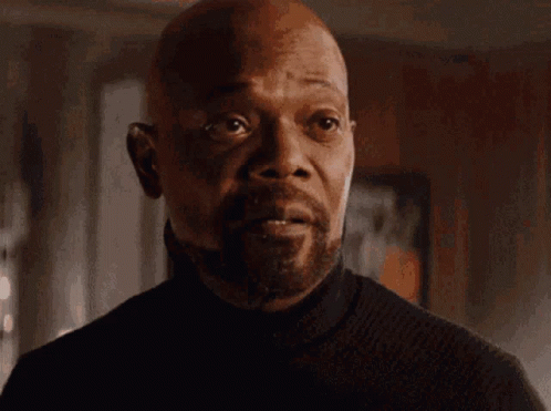 A Man With A Beard Is Wearing A Black Turtleneck Sweater And Looking At The Camera . GIF