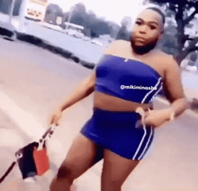 A Man With A Beard Is Wearing A Blue Crop Top And A Blue Skirt . GIF