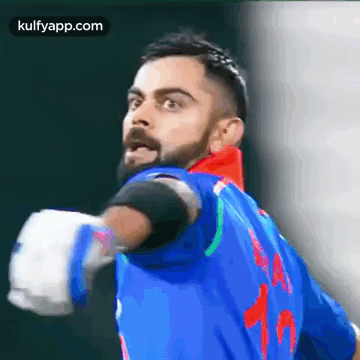 A Man With A Beard Is Wearing A Blue Jersey With The Number 15 On It . GIF